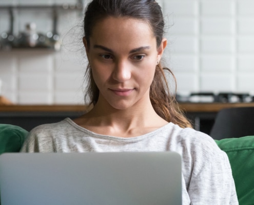 Horizontal photo mixed race female sitting on couch using computer