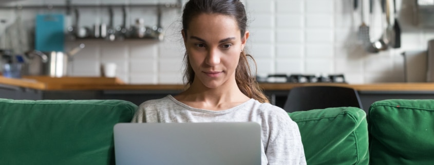 Horizontal photo mixed race female sitting on couch using computer