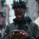 an attractive young man deeply engrossed in his smartphone within an urban setting With swift fingers