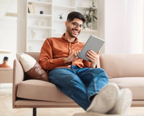 smiling young arab man using digital tablet at home