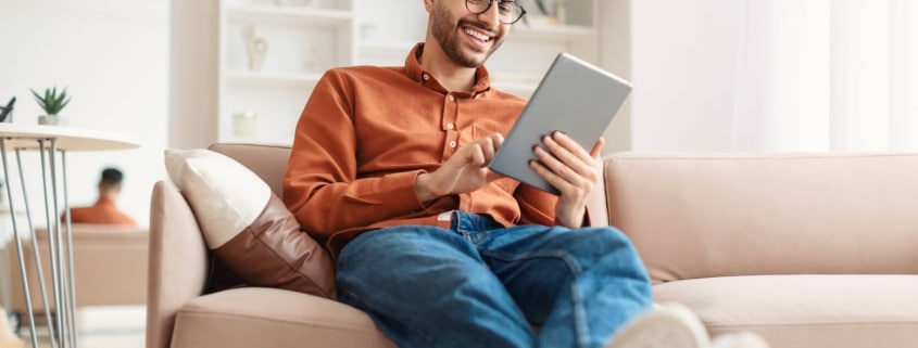 smiling young arab man using digital tablet at home